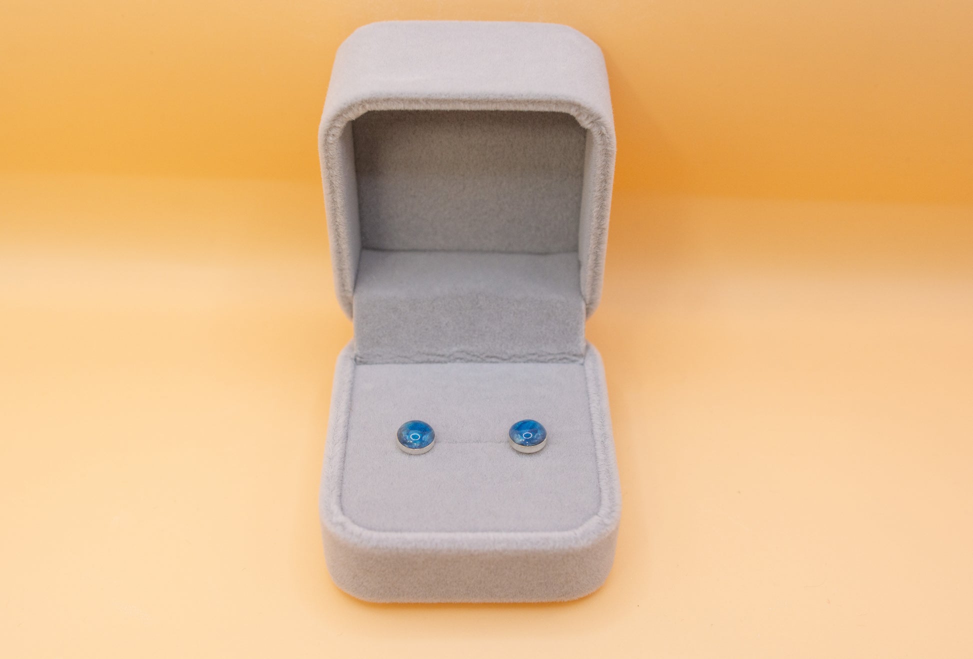 A pair of 925 silver stud memorial earrings, cobalt blue in colour, made with cremation ashes. presented in a plush grey jewellery box