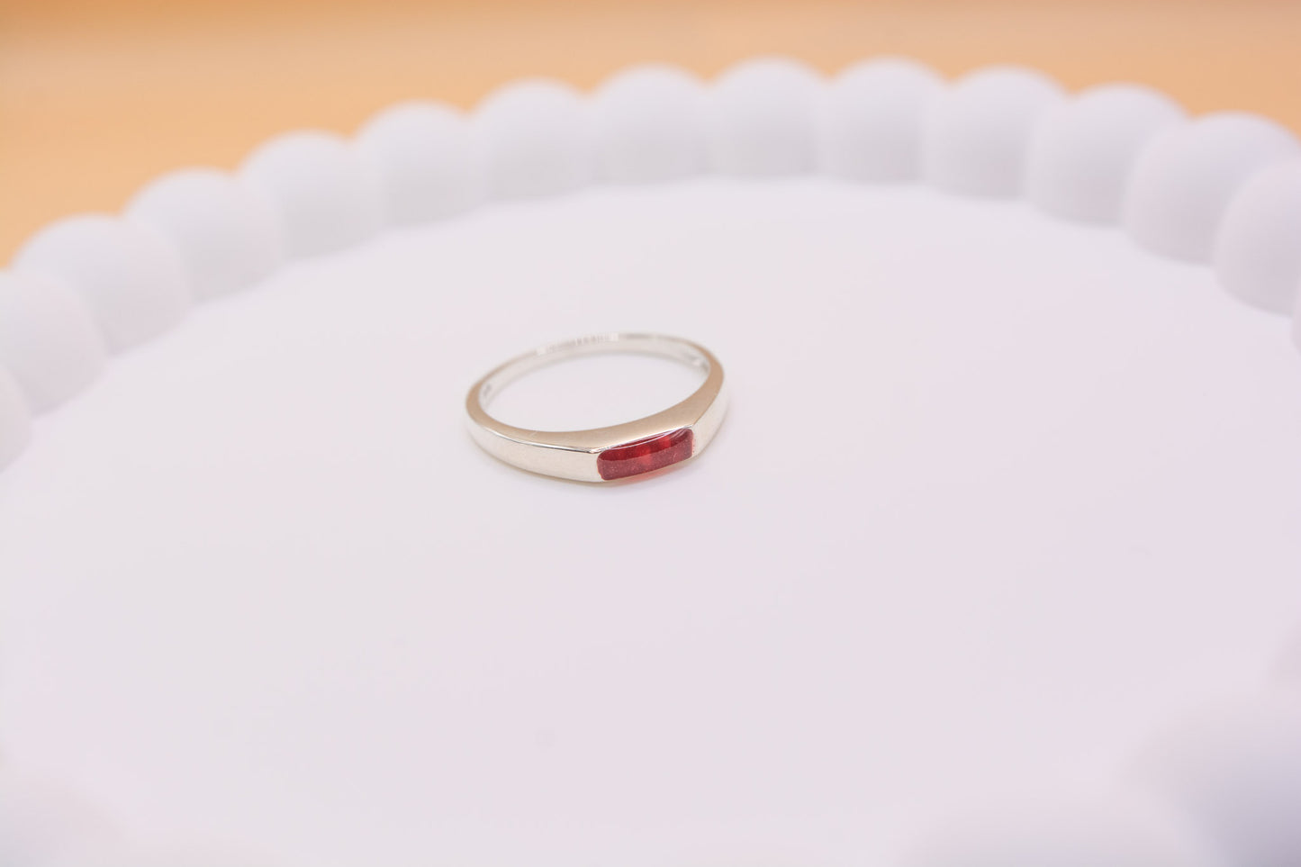 An angled close up view of a 925 silver keepsake memorial ring containing cremation ashes and red resin