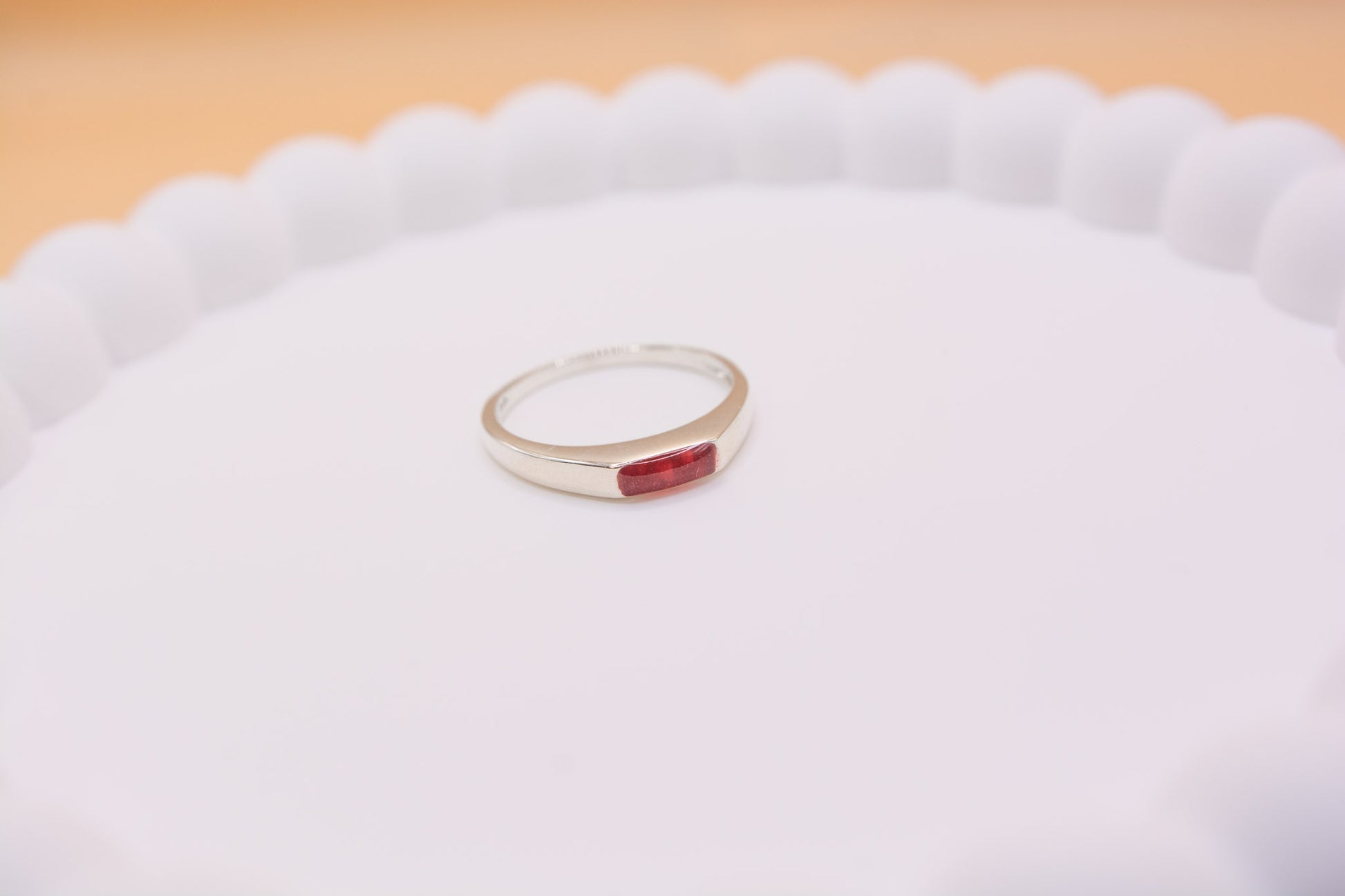 An angled close up view of a 925 silver keepsake memorial ring containing cremation ashes and red resin