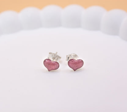 A close up shot of a pair of 925 sterling silver, pink coloured heart shaped stud earrings, containing cremation ashes