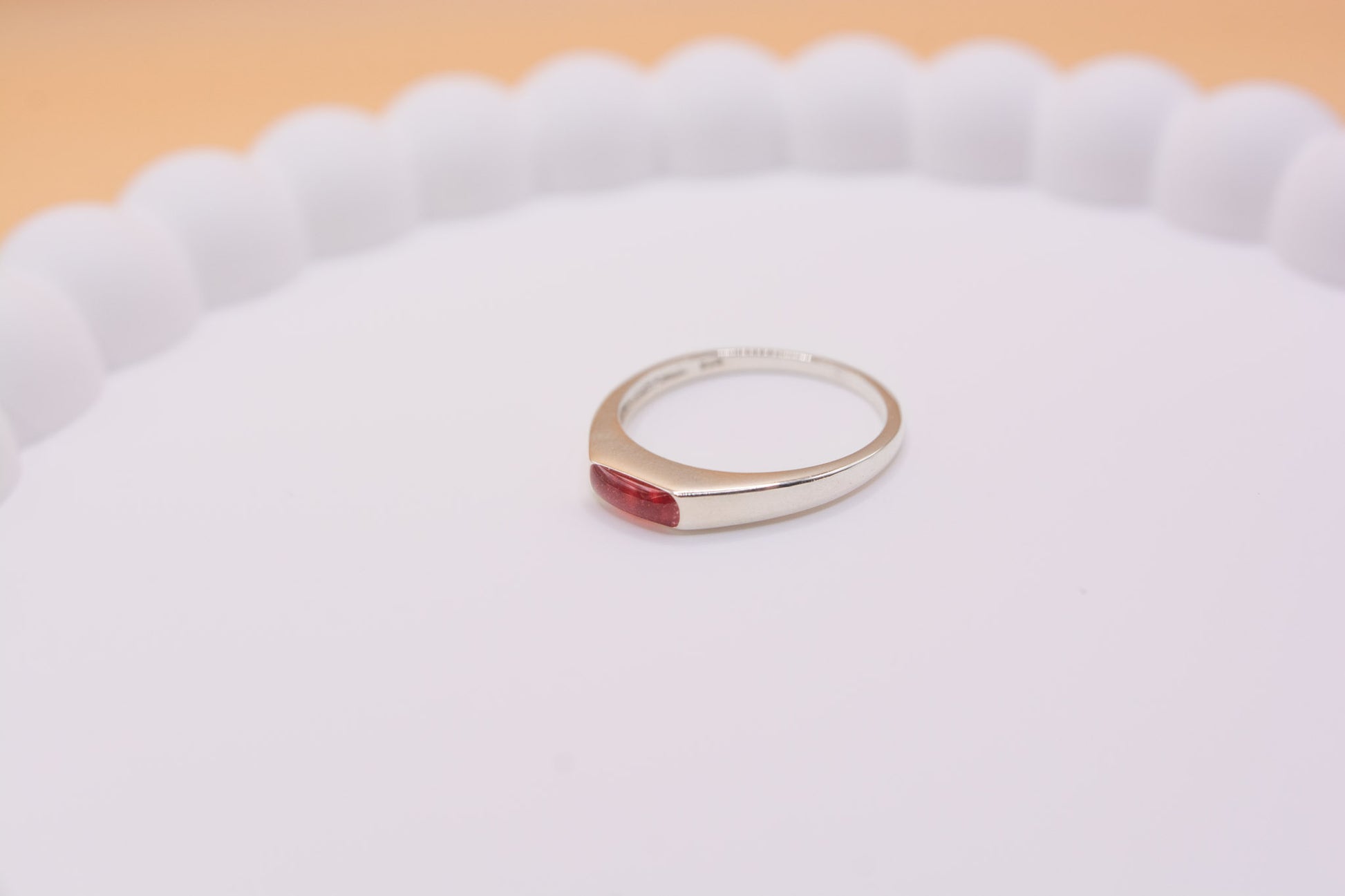 A 25 silver rectangle bezel memorial ring containing red coloured resin and pet ashes