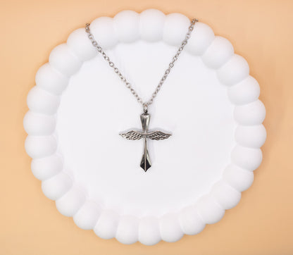 An aerial view of a beautiful stainless steel cross with angel wings pendant, which can be self-filled with cremation ashes or sand from the beach