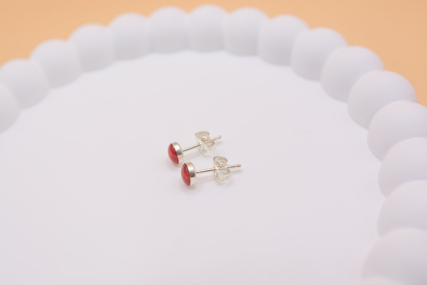 A close-up side view of a pair of keepsake cremation ashes memorial 925 silver stud earrings